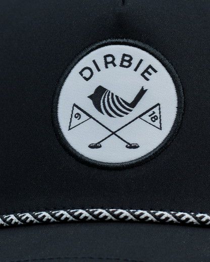 Close-up of a black golf cap featuring a circular white patch with the brand name &